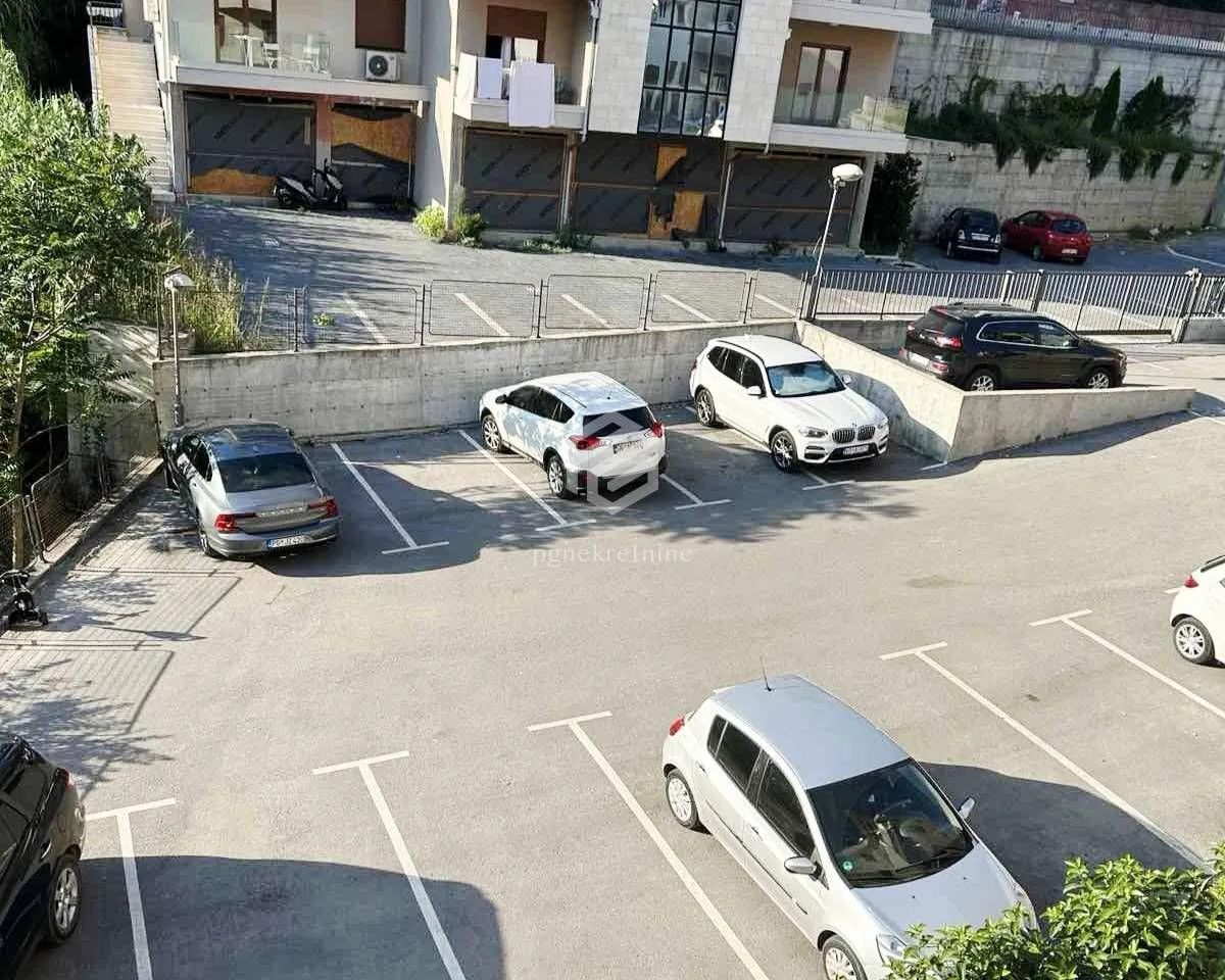 Pogled odozgo na parking prostor ispred zgrade sa parkiranim automobilima.