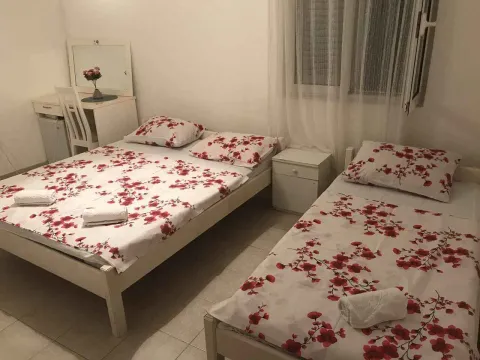 Simple bedroom with two beds featuring floral bedding and a vanity desk. - image 3