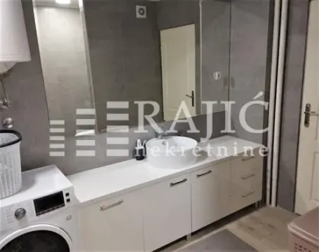 Bathroom with a sink, white vanity unit, and a washing machine. - image 5