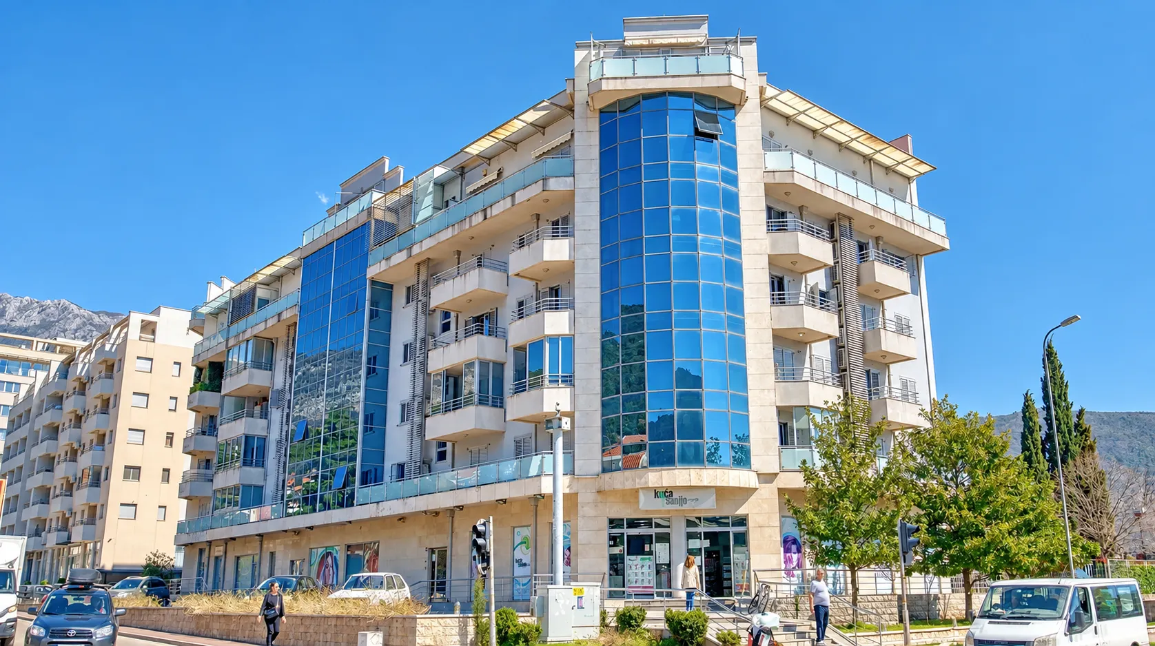 Exterior view of a modern residential building with a glass facade and balconies.