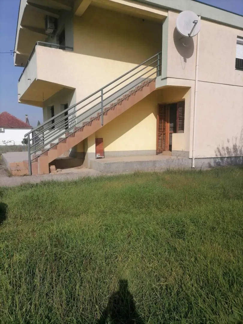 Spoljašnjost kuće sa vanjskim stepeništem i travnjakom.