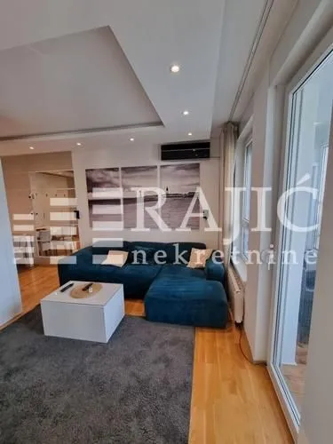 Modern living room with a sofa and hardwood flooring.