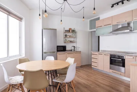 Bright kitchen with a dining table and wooden cabinets. - image 2