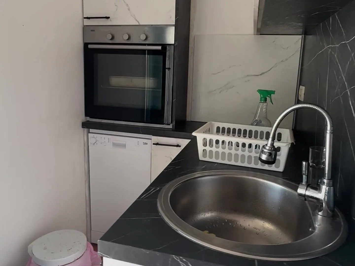 View of a kitchen area with a sink, oven, and countertop.