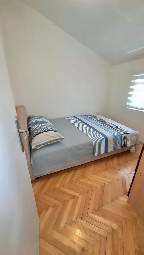 Small bedroom with a double bed and parquet flooring.