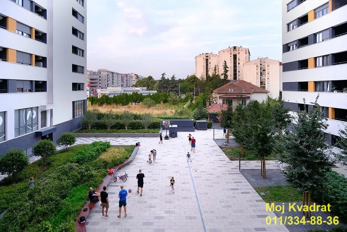 Landscaped courtyard between residential buildings with a pedestrian zone and greenery.