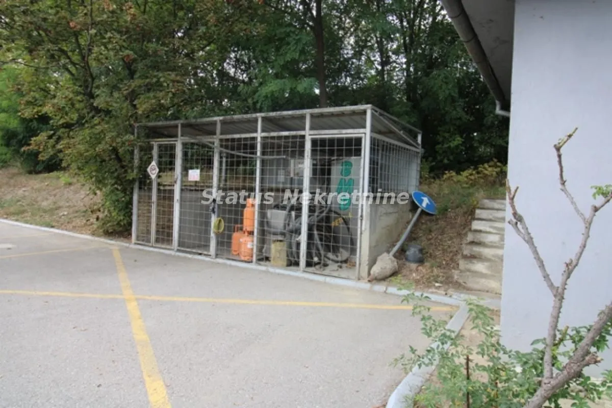 Exterior part of the building with a fenced storage area and parking space in the background.