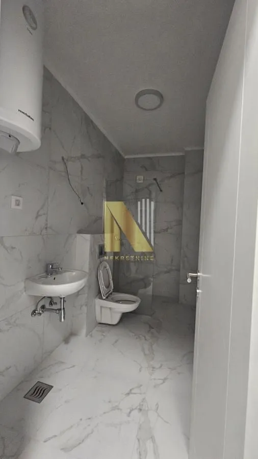 Newly equipped bathroom with marble tiles, washbasin and toilet.