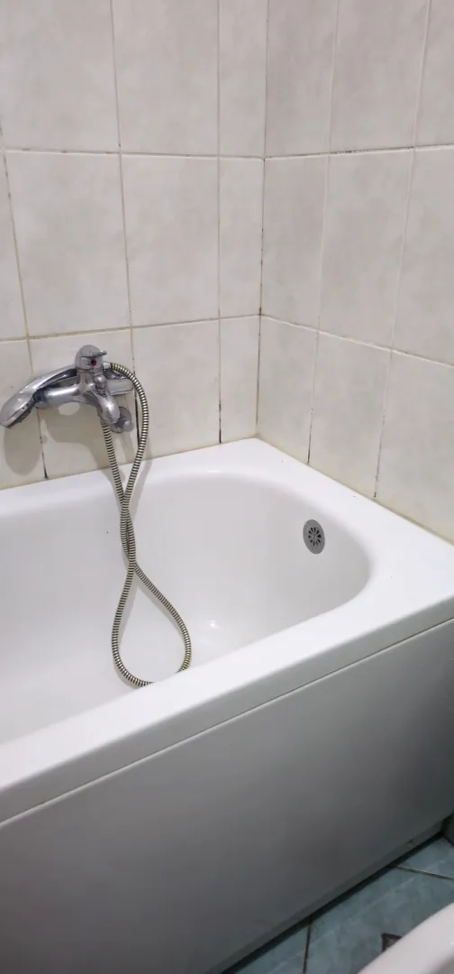 Bijela kada sa slavinom i keramičkim pločicama na zidu.
