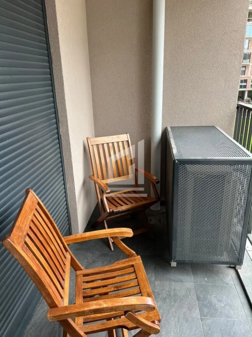 Manji namješteni balkon sa drvenim stolicama i zaštitnom ogradom.