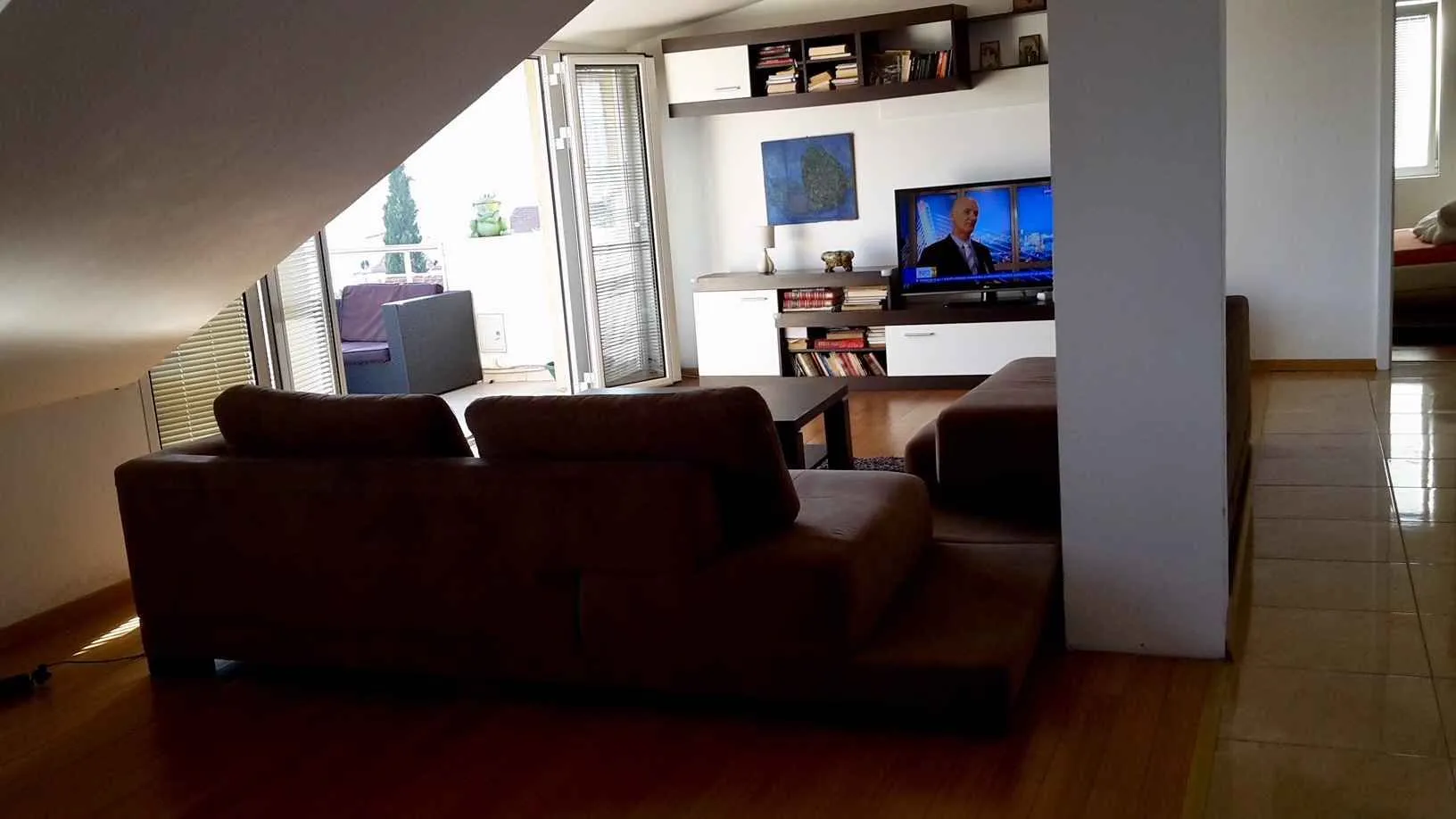 Svijetla dnevna soba sa udobnim namještajem i izlazom na balkon.