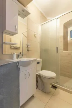Manje kupatilo sa tuš kabinom, umivaonikom i toaletom u svijetlim tonovima. - image 4