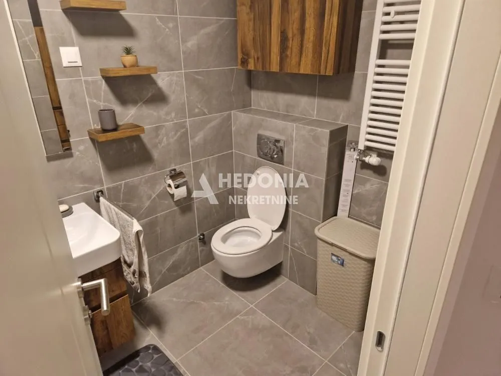 Modernly equipped bathroom with grey tiles and wooden details.