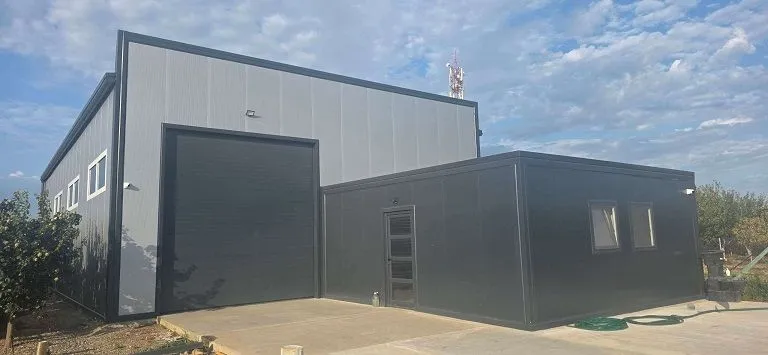 Exterior of a modern industrial building with a roll-up door and driveway.