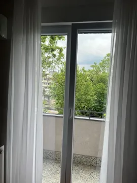 View through the balcony door to the terrace and greenery. - image 3