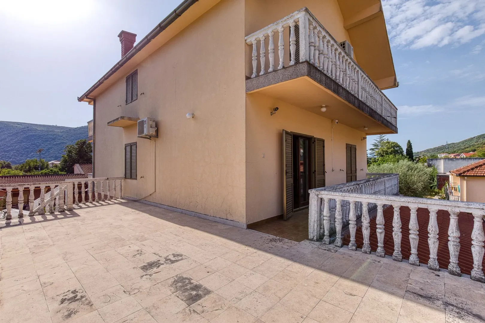 Eksterijer kuće sa prostranom terasom i balkonom.