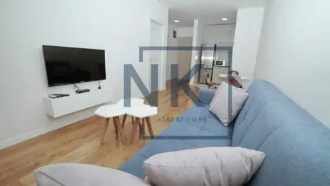 Dnevna soba sa plavom garniturom, televizorom i pogledom prema kuhinji. - image 4