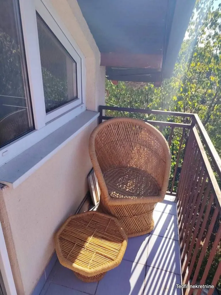 Manji natkriveni balkon sa pletenom foteljom i stočićem.