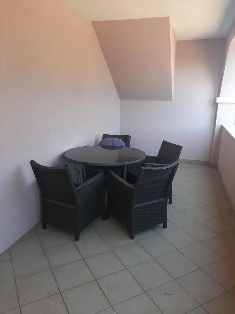 Covered terrace with seating furniture and a table.