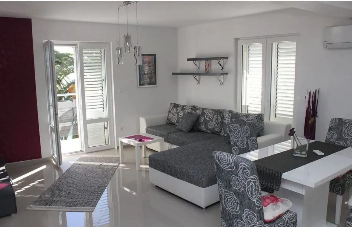 Bright and spacious living room with sofa set and dining table.