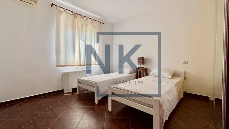 Bedroom with two single beds, a window, and an air conditioning unit.