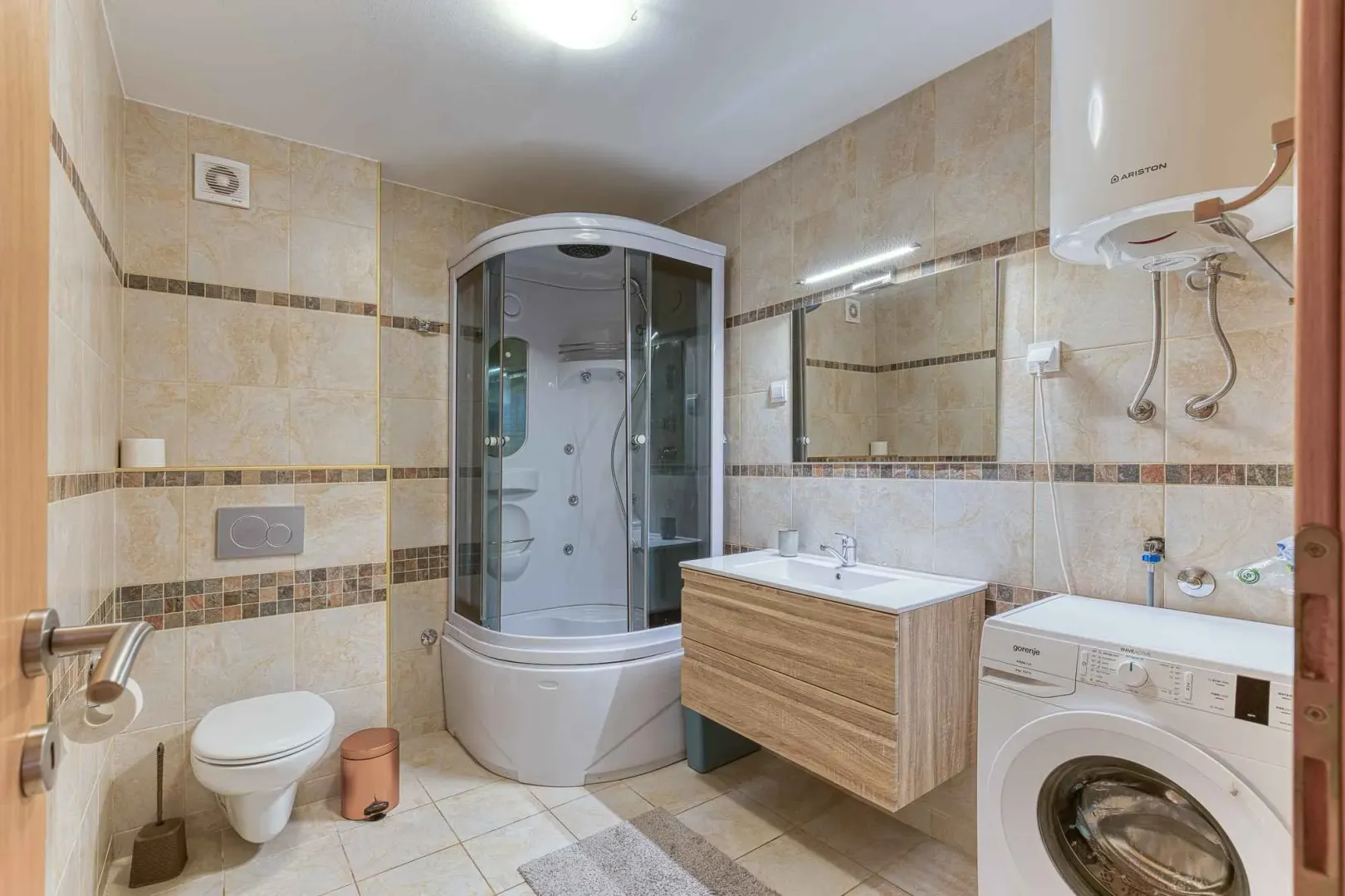 Bathroom equipped with a shower cabin, washbasin, toilet, and washing machine.