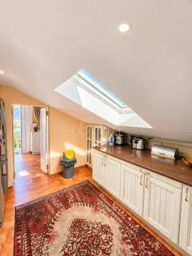 Attic kitchen with white cabinetry and a skylight. - image 9