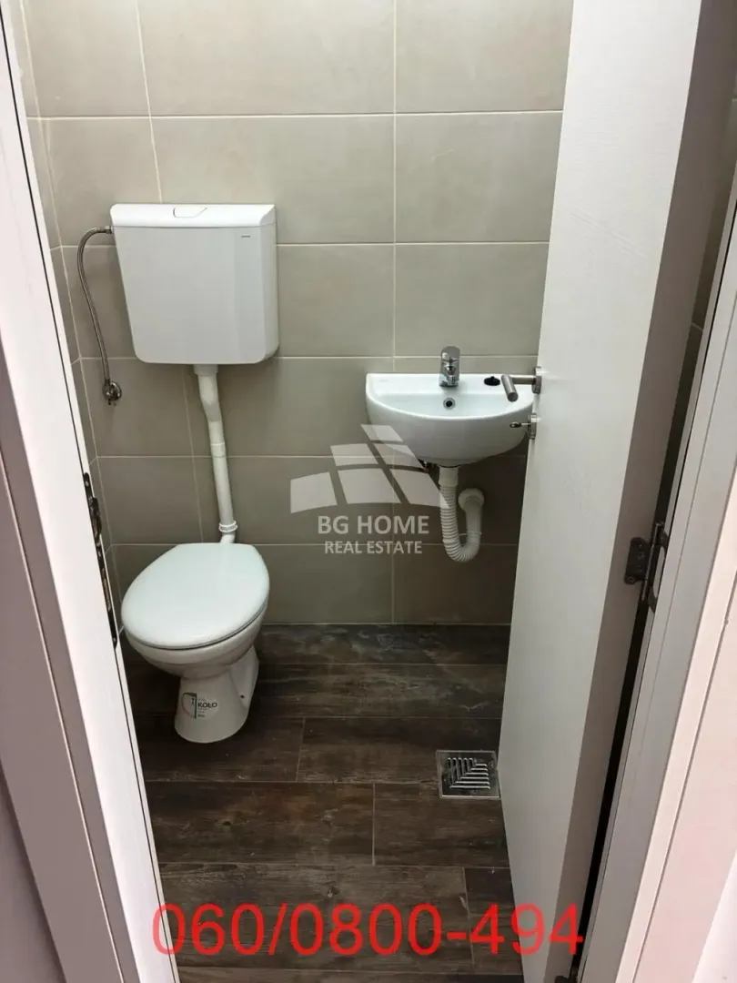 Smaller bathroom with a toilet and a sink in a tiled space.