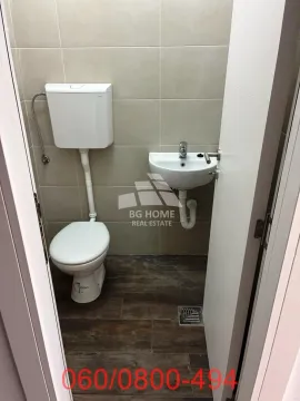 Smaller bathroom with a toilet and a sink in a tiled space. - image 4