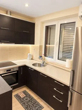 Small kitchen with dark cabinetry, built-in appliances, and a window. - image 4