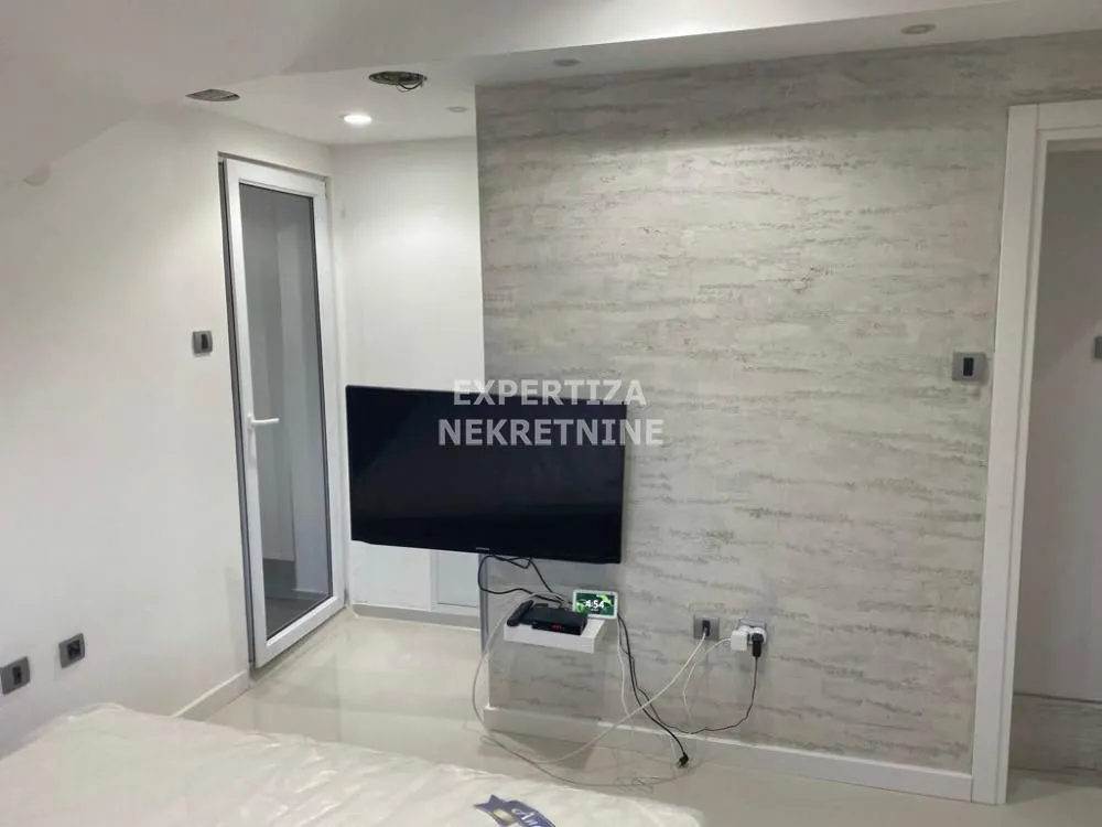 Furnished bedroom with a wall-mounted TV.
