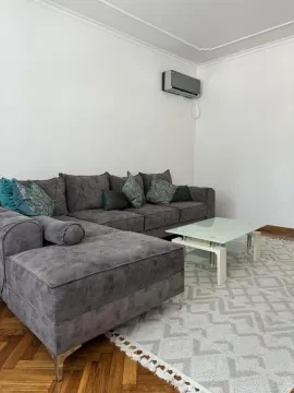 Dnevna soba sa ugaonom garniturom, stočićem i klima uređajem na zidu. - image 5
