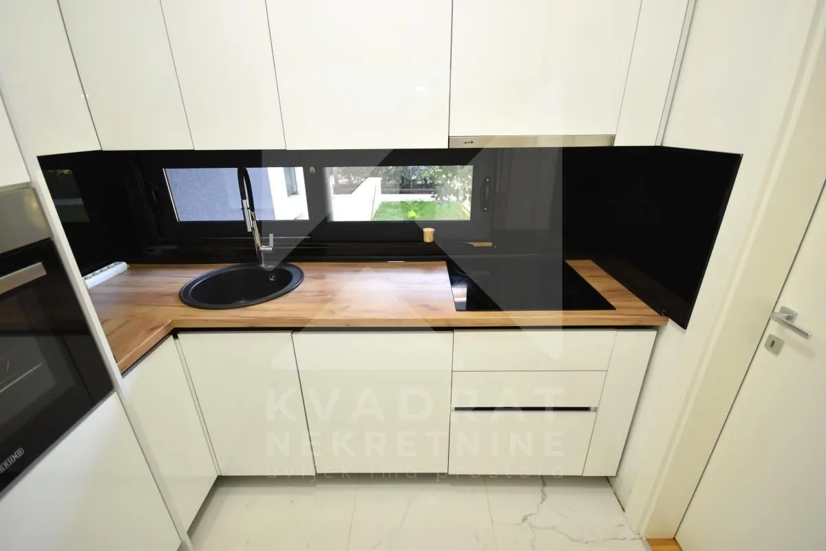 Modern white kitchen with a sink and a built-in cooktop.