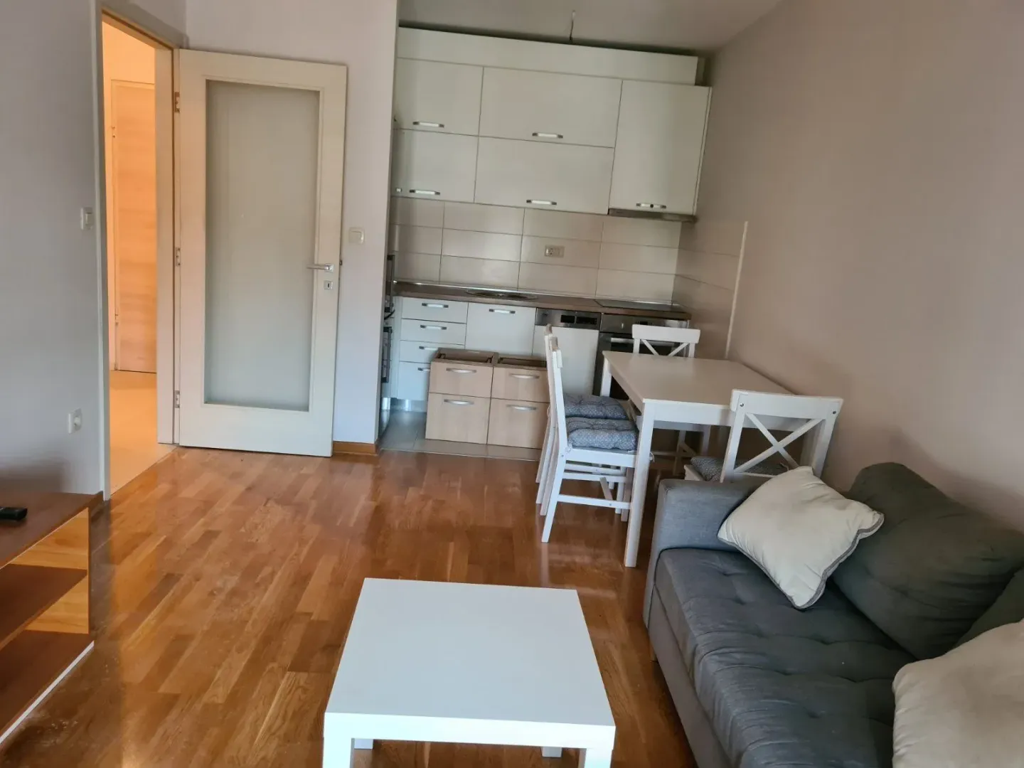 Dnevna soba sa kuhinjom i trpezarijskim stolom u svijetlom tonu.