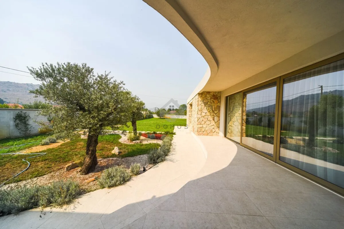 Covered terrace and paved courtyard with a landscaped garden in front of the house.