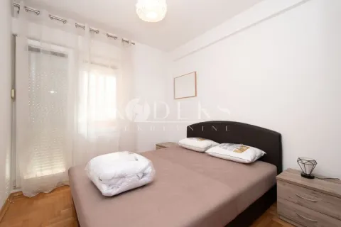 Manja spavaća soba sa bračnim krevetom, noćnim stočićima i prozorom sa bijelim zavesama. - image 7