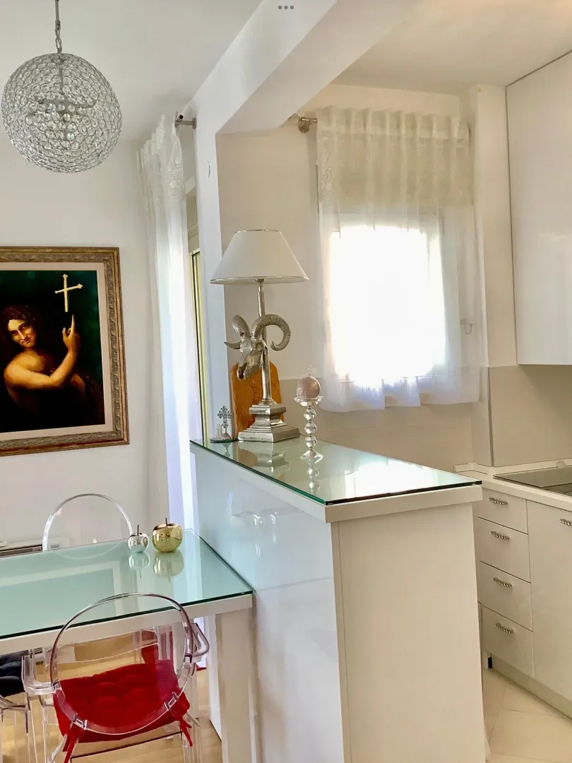 Moderna kuhinja sa trpezarijskim stolom i staklenim detaljima.