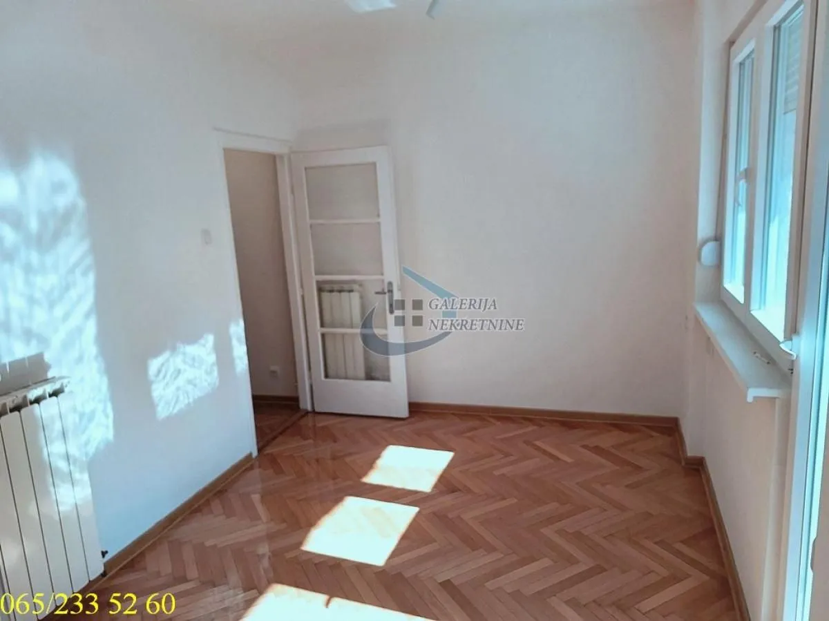 Empty room with parquet flooring and white walls.
