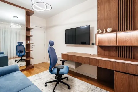 Moderna dnevna soba sa radnim stolom, plavom foteljom i TV-om na zidu. - image 7