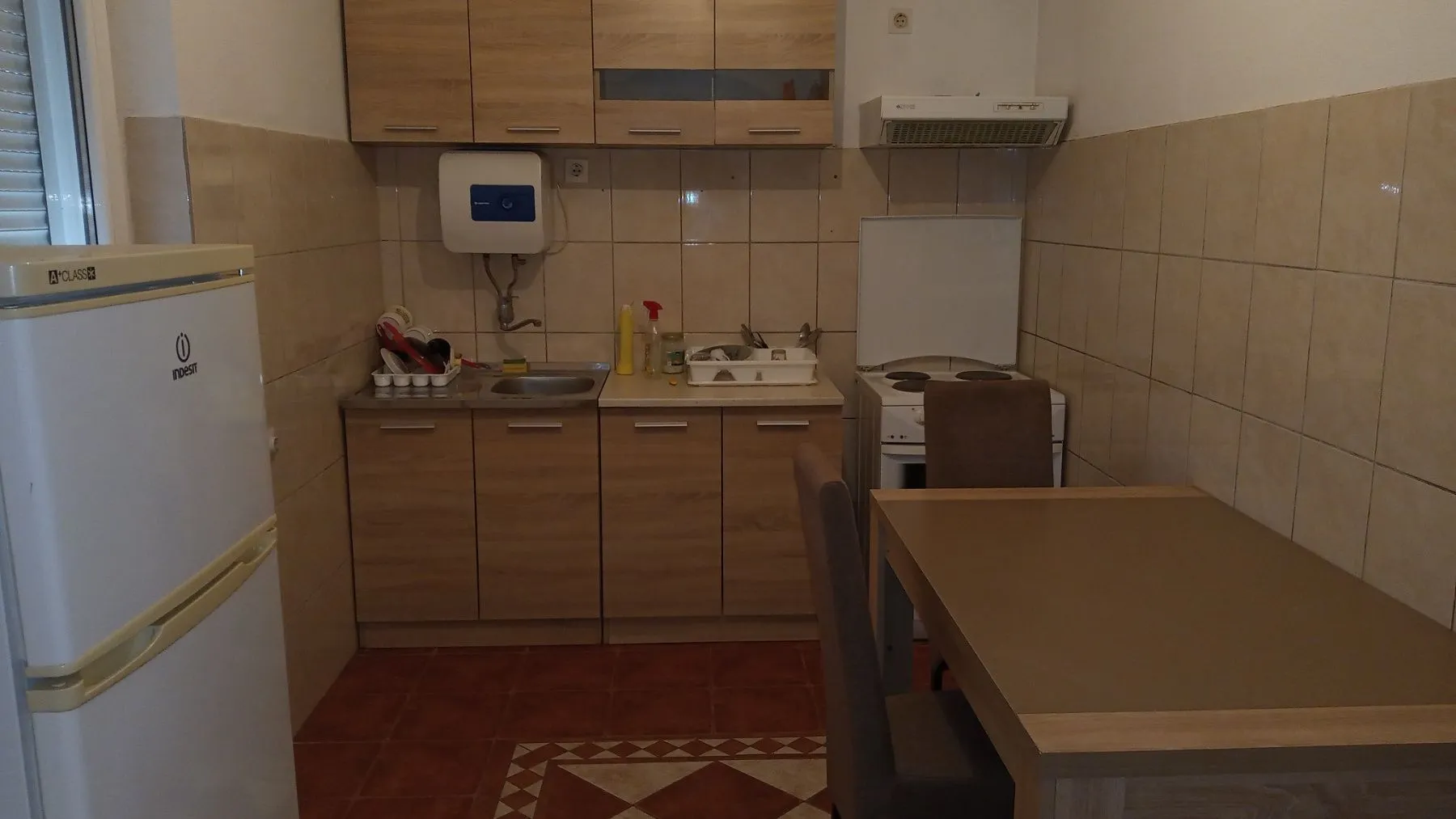A kitchen with wooden cabinets, a refrigerator, and a dining table.