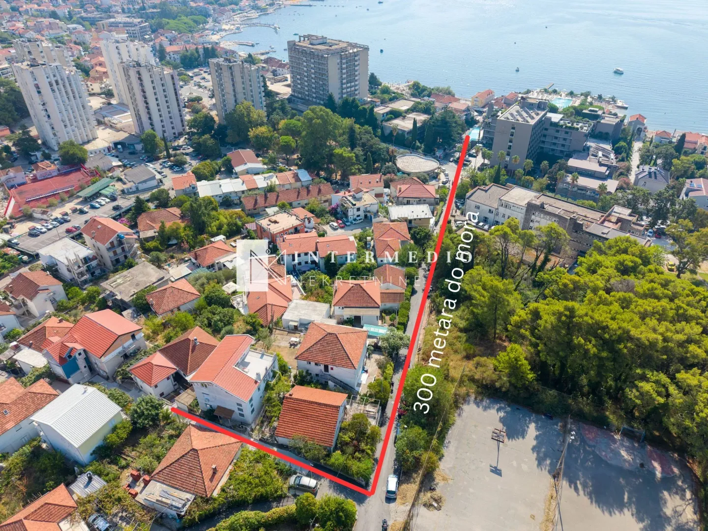 Vazdušni snimak lokacije nekretnine sa označenim granicama placa u naselju blizu mora.