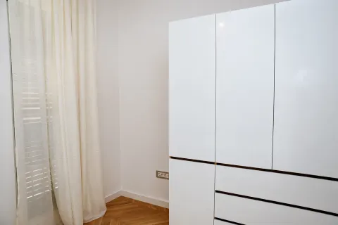 Bijeli garderober u sobi sa drvenim podom i prozorom sa zavjesama. - image 11