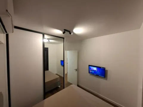 Furnished bedroom with a bed, mirrored wardrobe, and a wall-mounted TV. - image 3