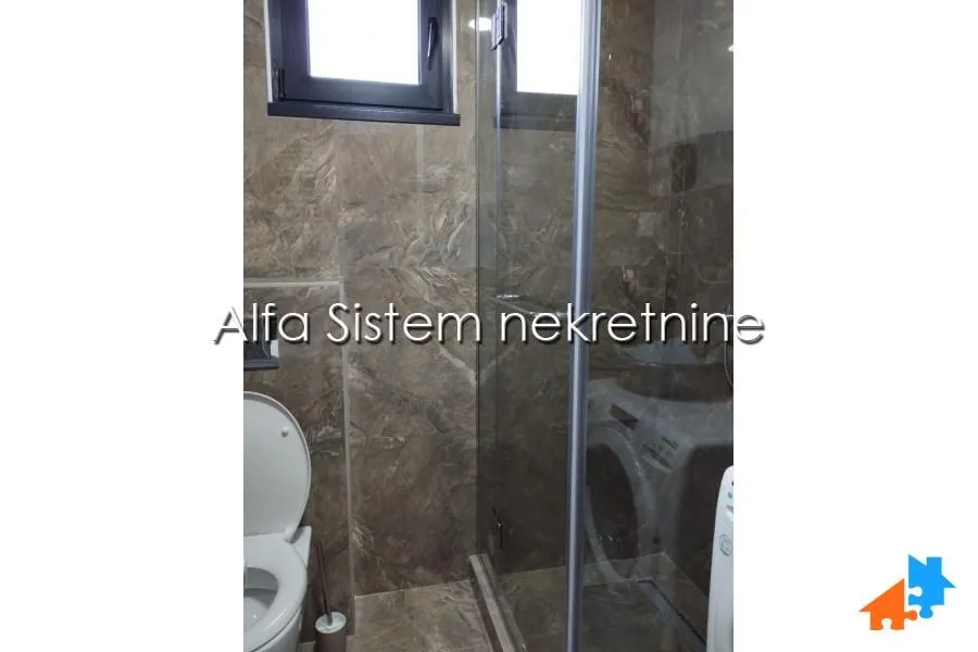 Bathroom with a shower cabin, toilet, and brown-toned tiles.