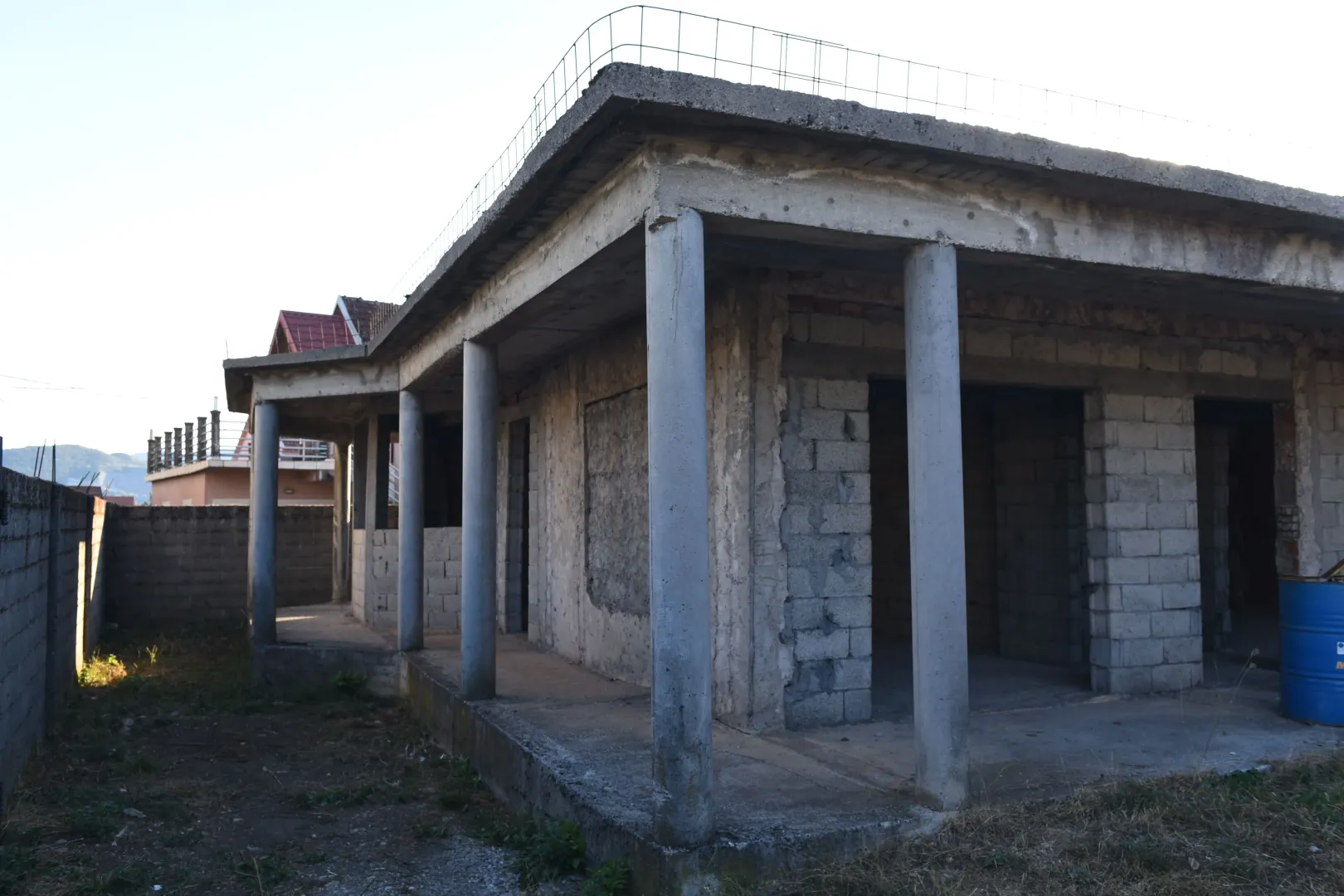 Eksterijer kuće u izgradnji sa betonskim stubovima i terasom.