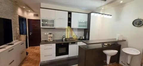 Kuhinja opremljena belim elementima i šankom sa barskim stolicama. - image 4