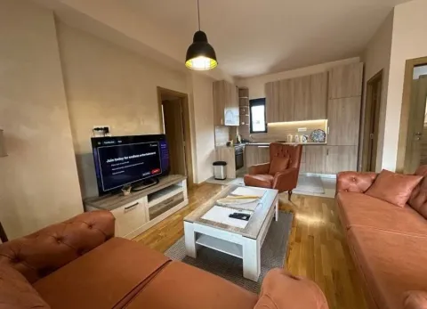 Living room with sofas, a TV, and a kitchen in the background. - image 10