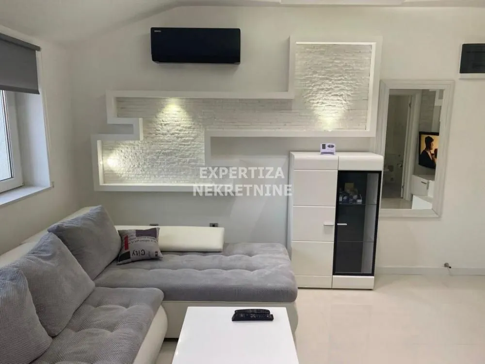 Living room with a sectional sofa, white furniture unit, and a decorative feature wall.