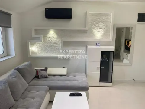 Living room with a sectional sofa, white furniture unit, and a decorative feature wall. - image 2