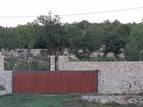 Stone fence with a courtyard gate and greenery in the background. - image 2